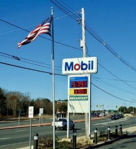 A mobil gas station with an american flag on the side of the road.
