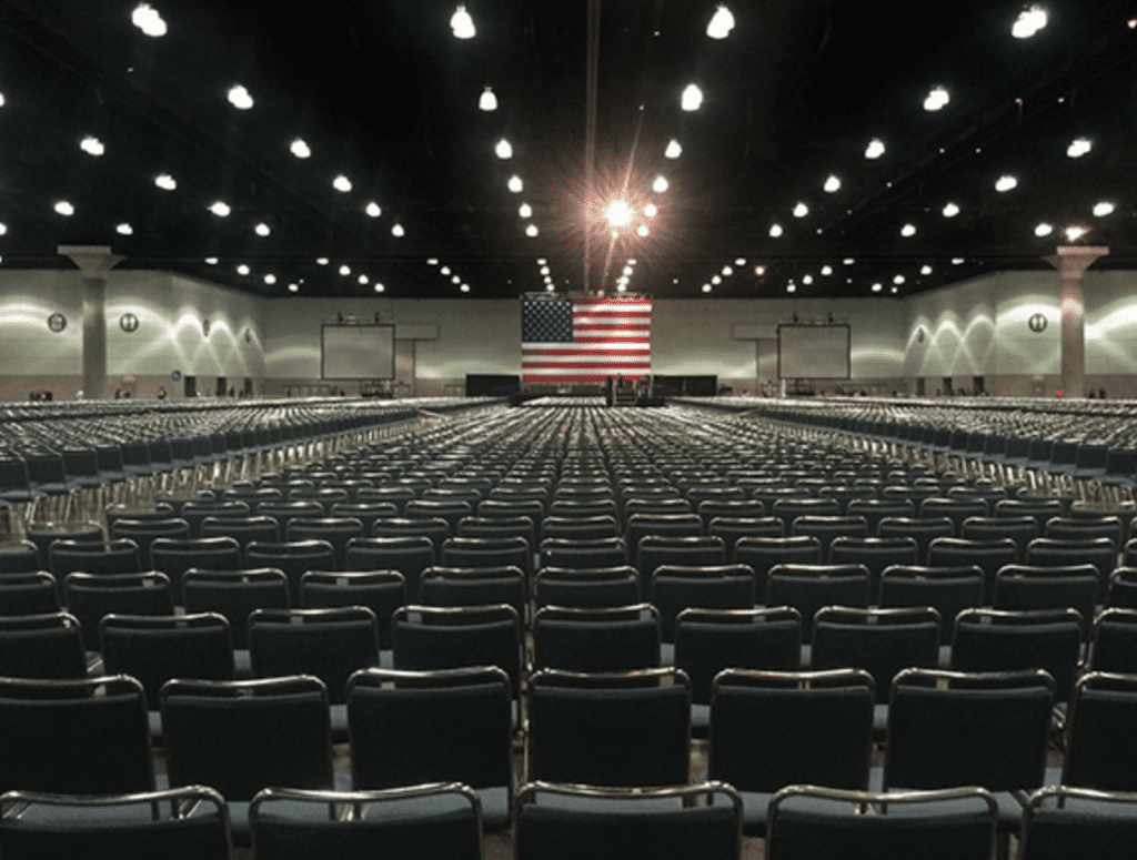 An empty room with rows of chairs and an american flag.