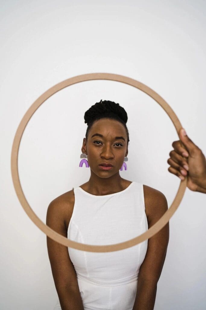 A woman holding a hoop in front of a white wall.