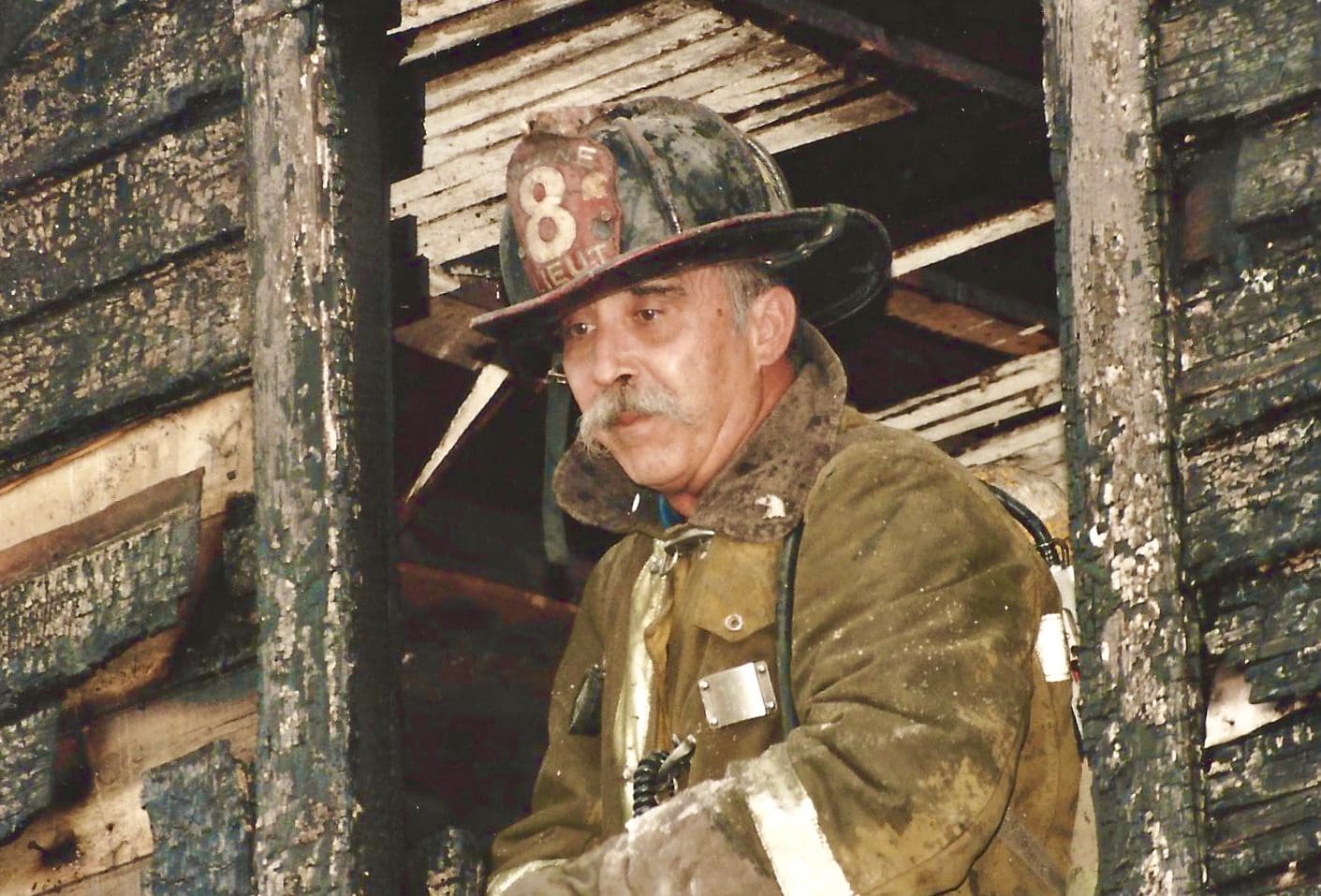 A firefighter standing in the window of an old house.