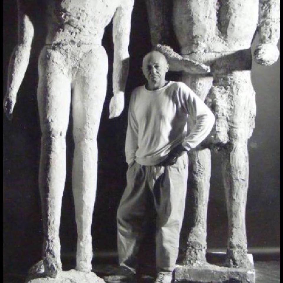 A man standing next to two large sculptures.