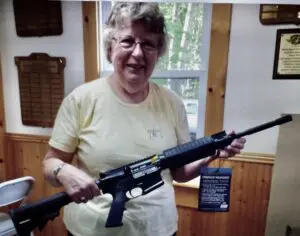 A woman holding a rifle in a room.