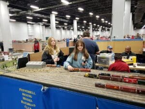 Two girls looking at model trains at a convention.