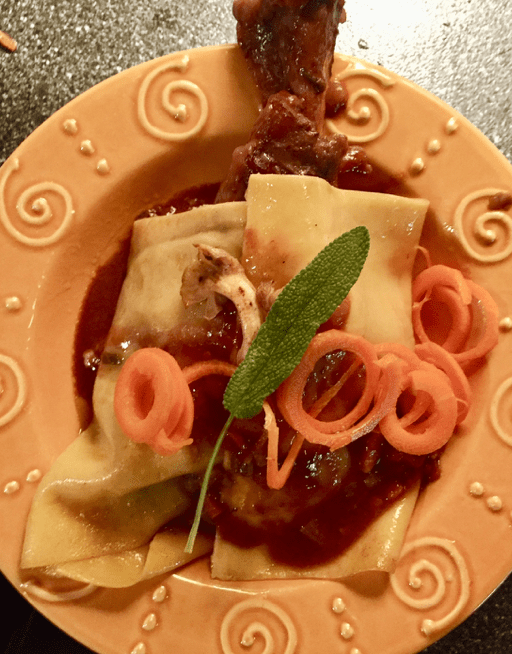 A plate of pasta with sauce and sprigs of sage.
