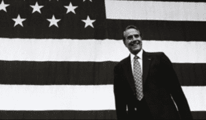 President barack obama standing in front of an american flag.