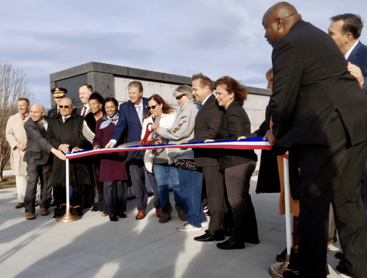 A group of people cutting a ribbon in front of a building.