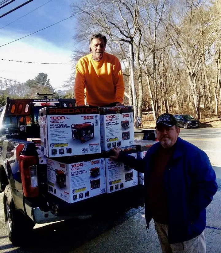 Two men standing on the back of a truck with boxes.
