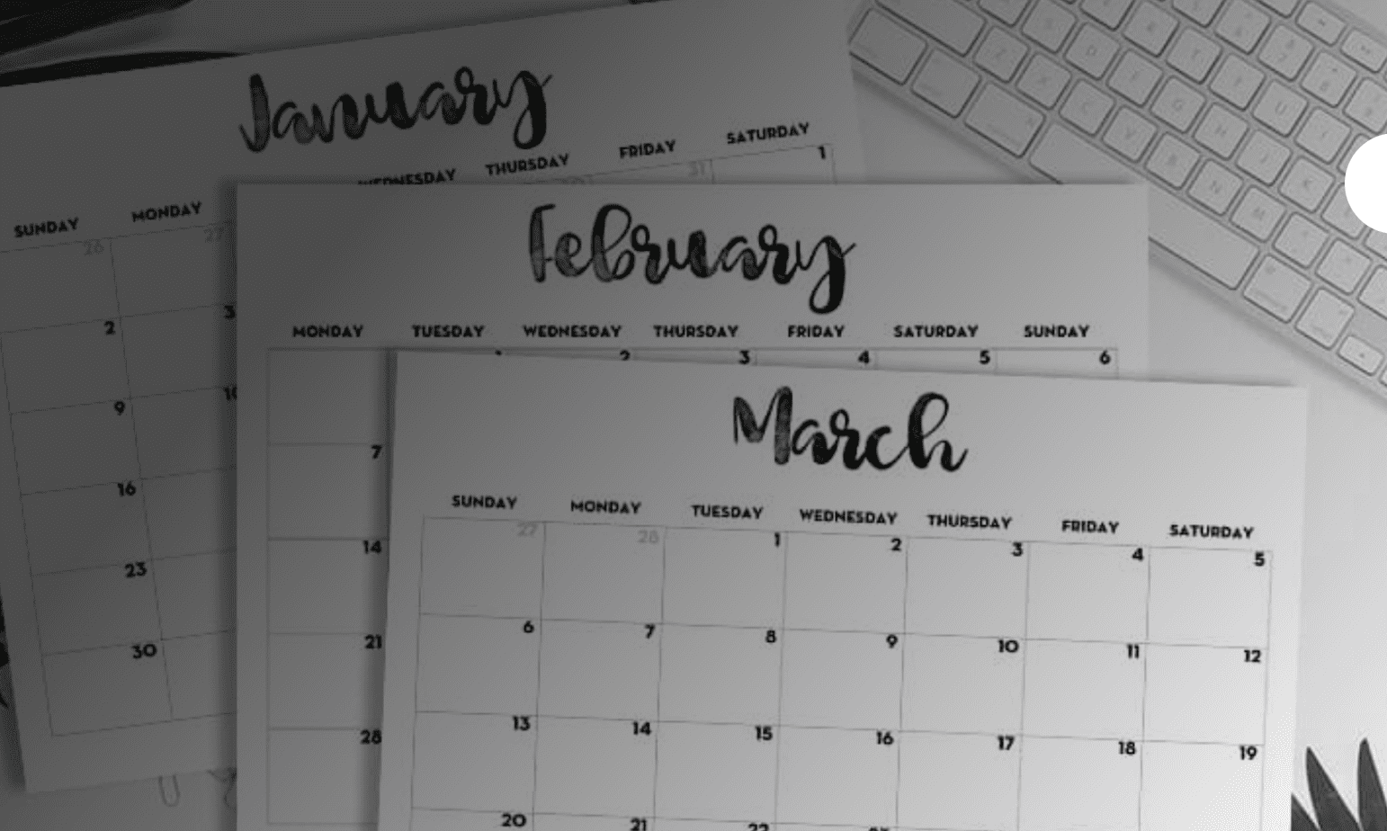 A printable calendar on a desk next to a keyboard.