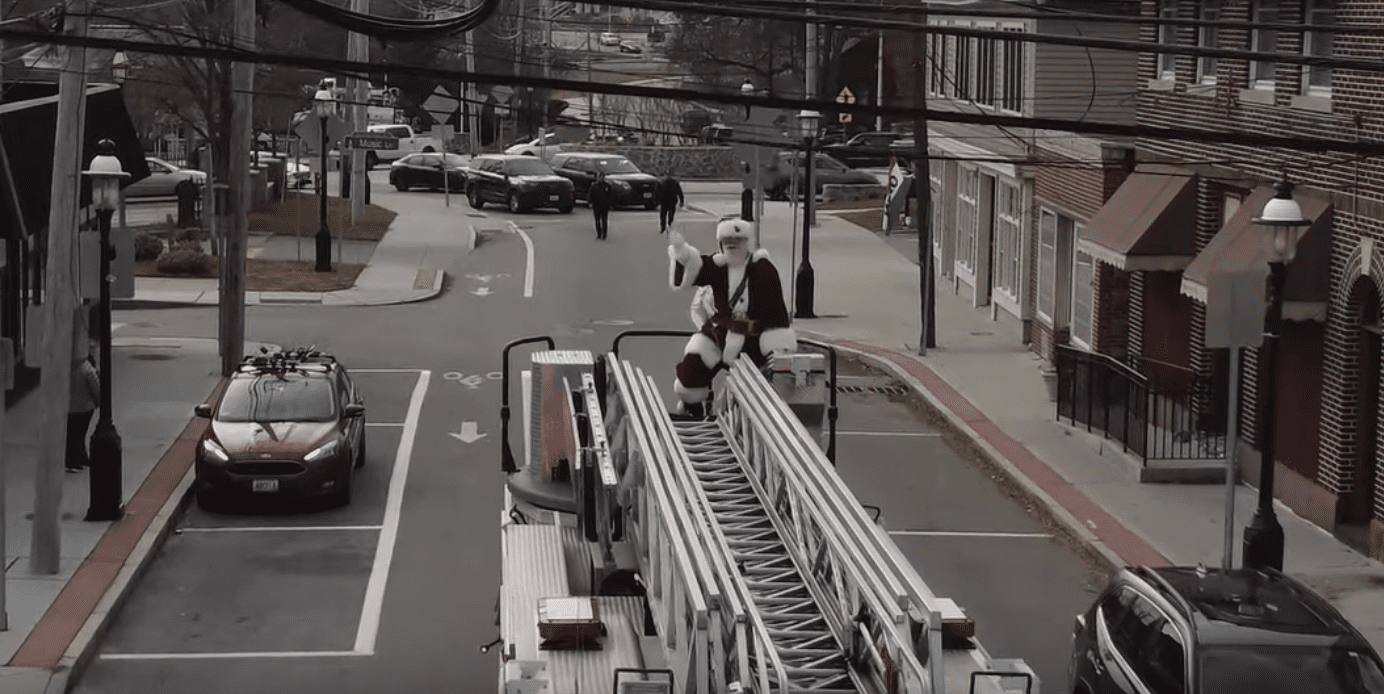 A fire truck on a street with a man on top of it.