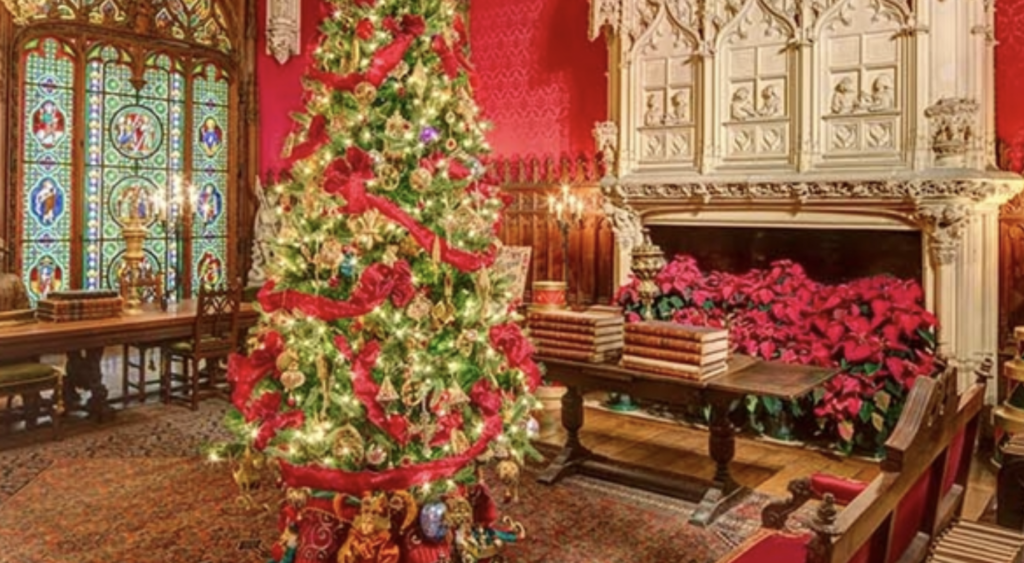 A christmas tree in an ornate room with stained glass windows.