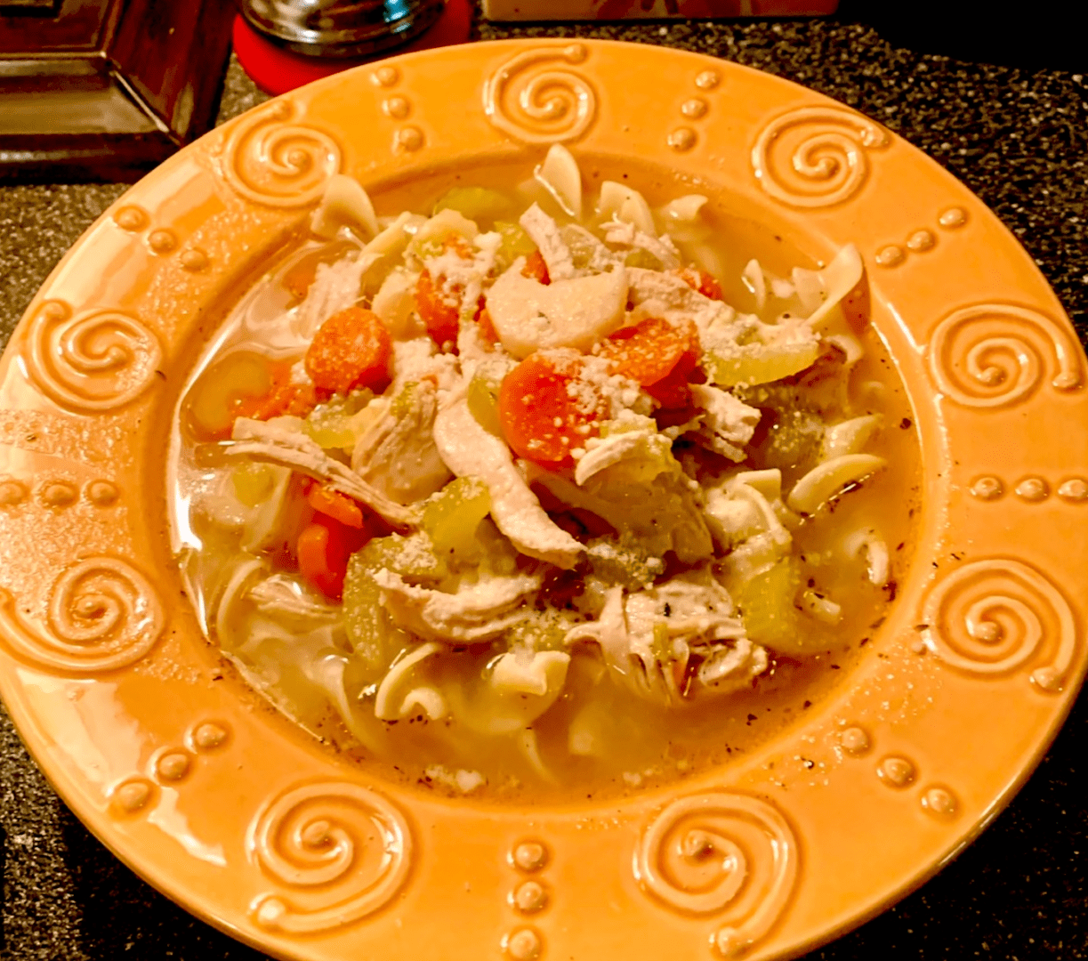 A bowl of chicken noodle soup on a table.