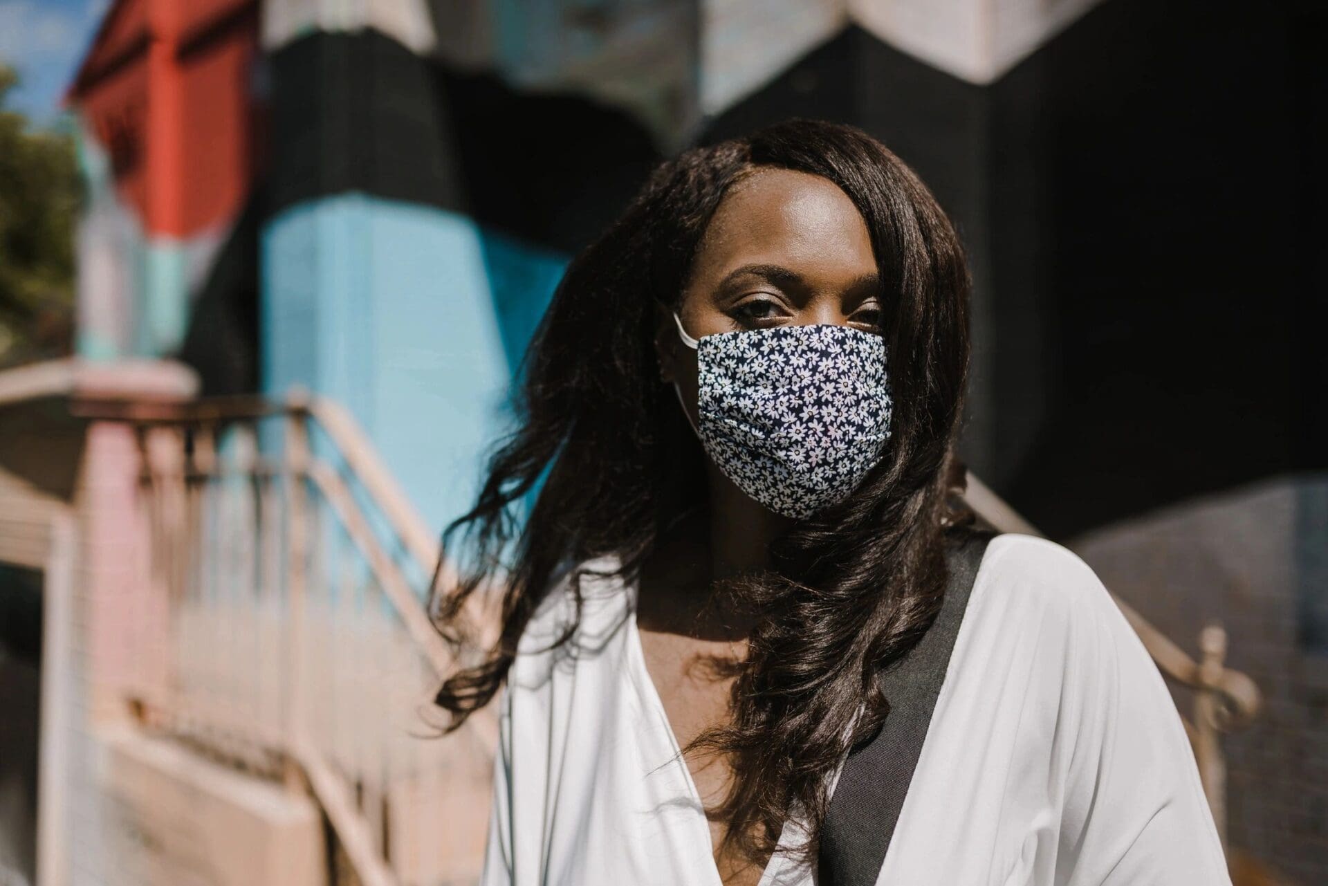 A woman wearing a face mask in front of a building.