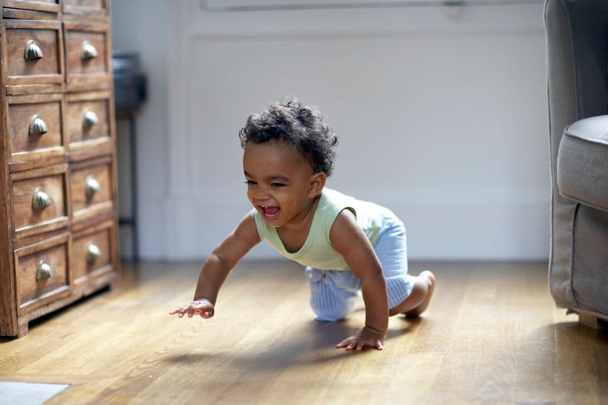 A baby crawling on the floor in a living room.
