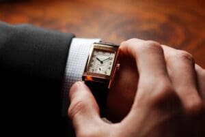 A man in a suit is holding a watch.