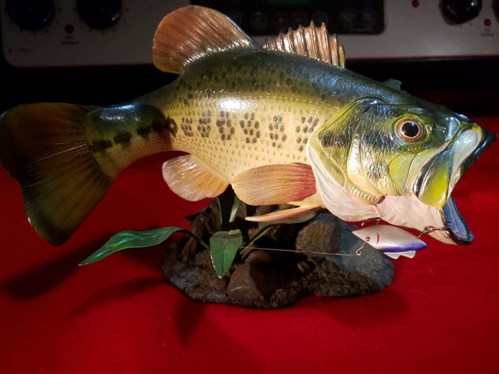 A statue of a large bass fish on a table.