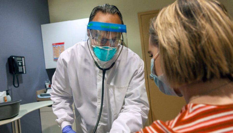 A man in a protective mask is examining a patient.