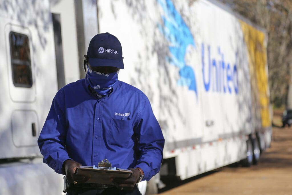 A man holding a clipboard in front of a truck.