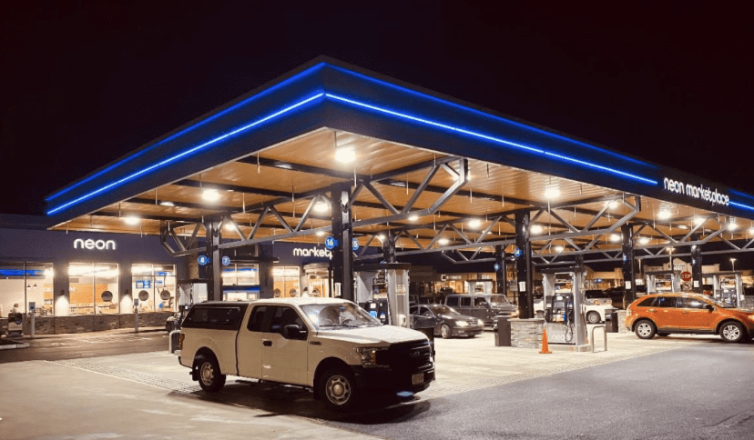 Two cars parked at a gas station at night.