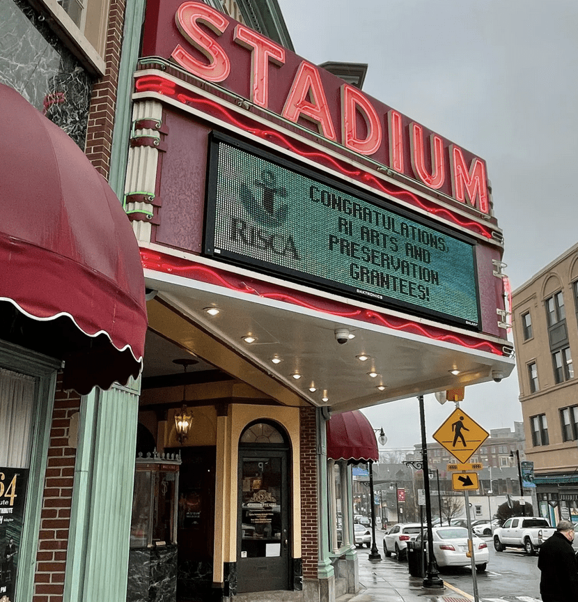 The front of a theater with a sign that says stadium.