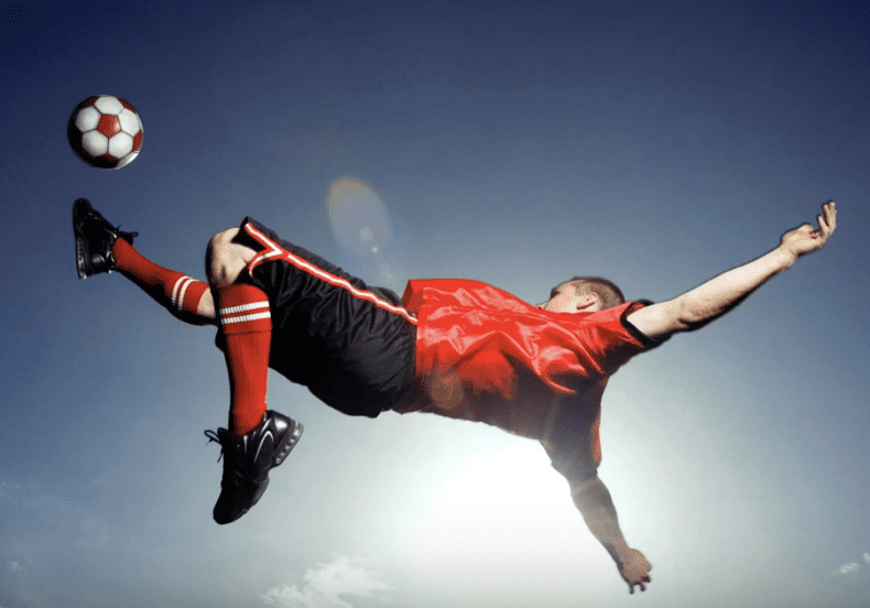 A soccer player kicking a ball in the air.