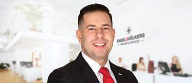 A man in a suit and tie smiling in an office.