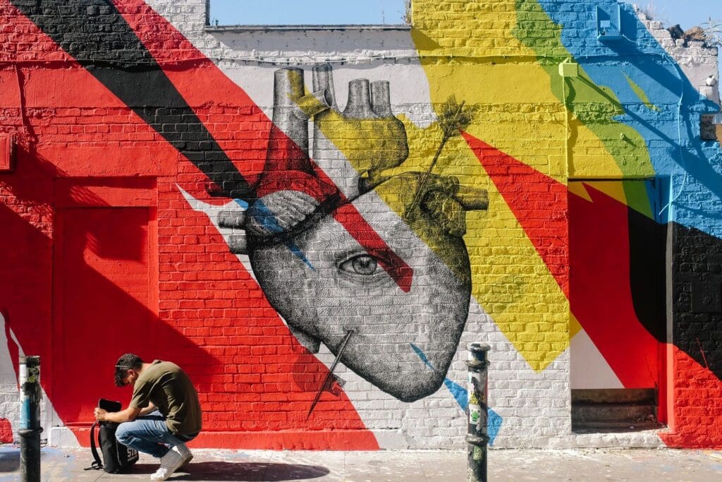 A man is painting a heart on the side of a building.