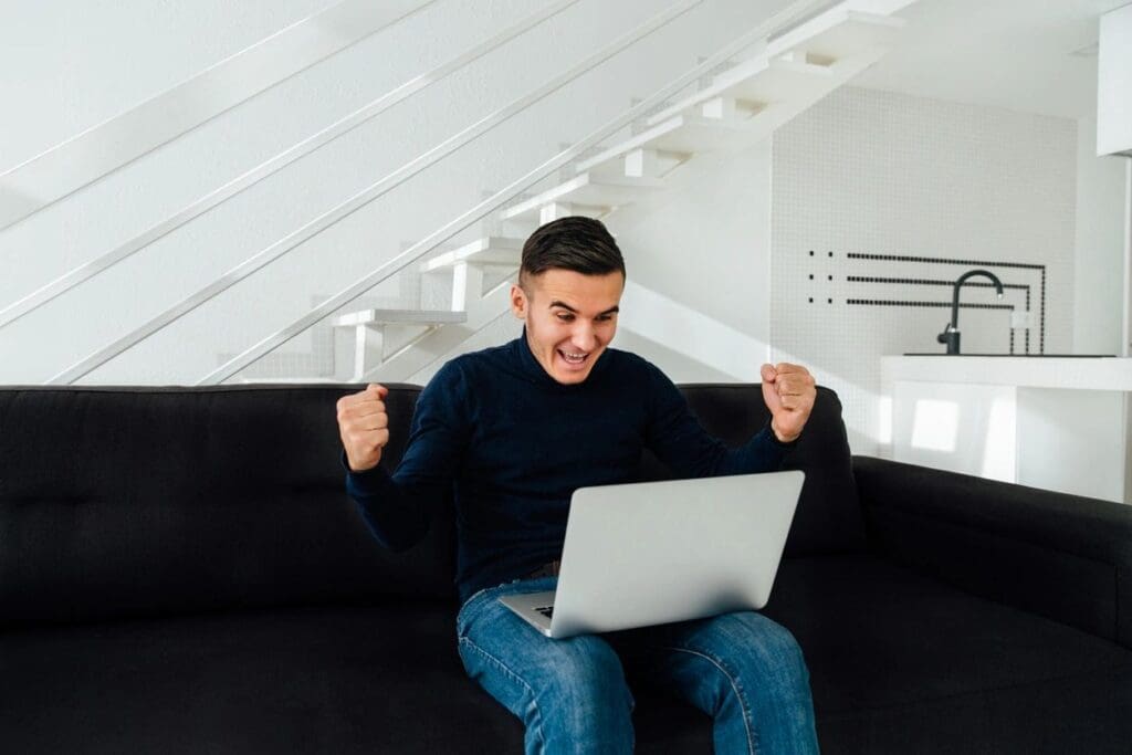 A man is sitting on a couch and using a laptop.