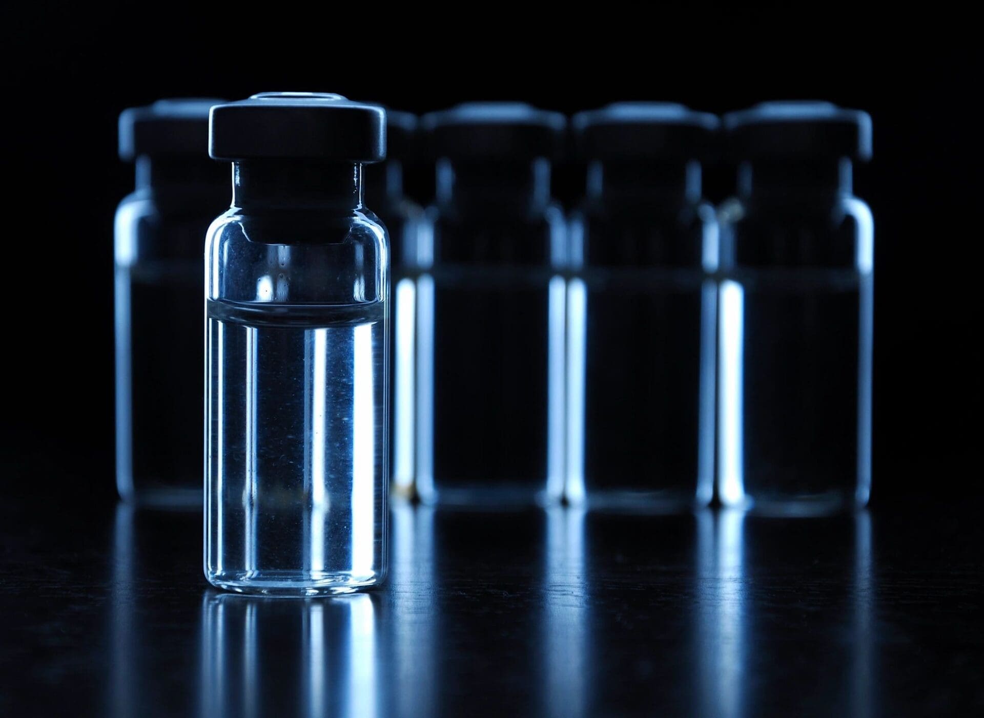 A group of glass vials on a dark surface.
