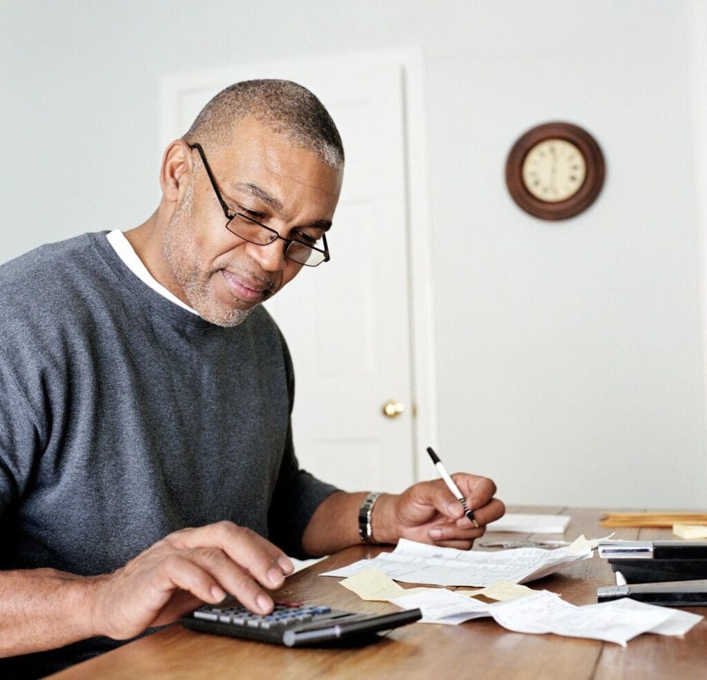 A man sitting at a table with papers and a calculator.