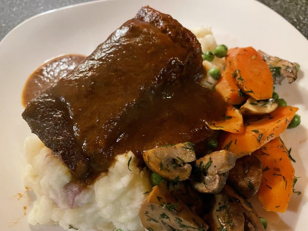 A plate with mashed potatoes, carrots and gravy.