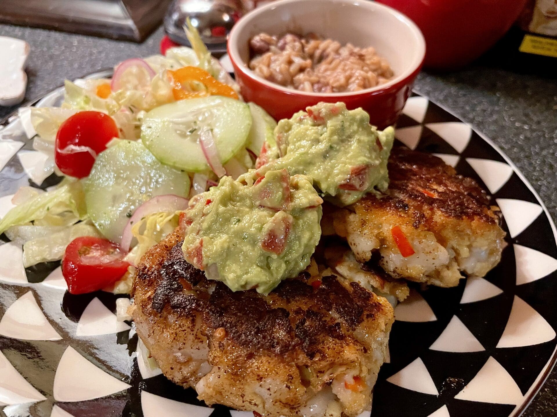 Crab cakes with guacamole and salad on a plate.