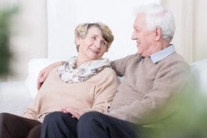 An older couple sitting on a couch.