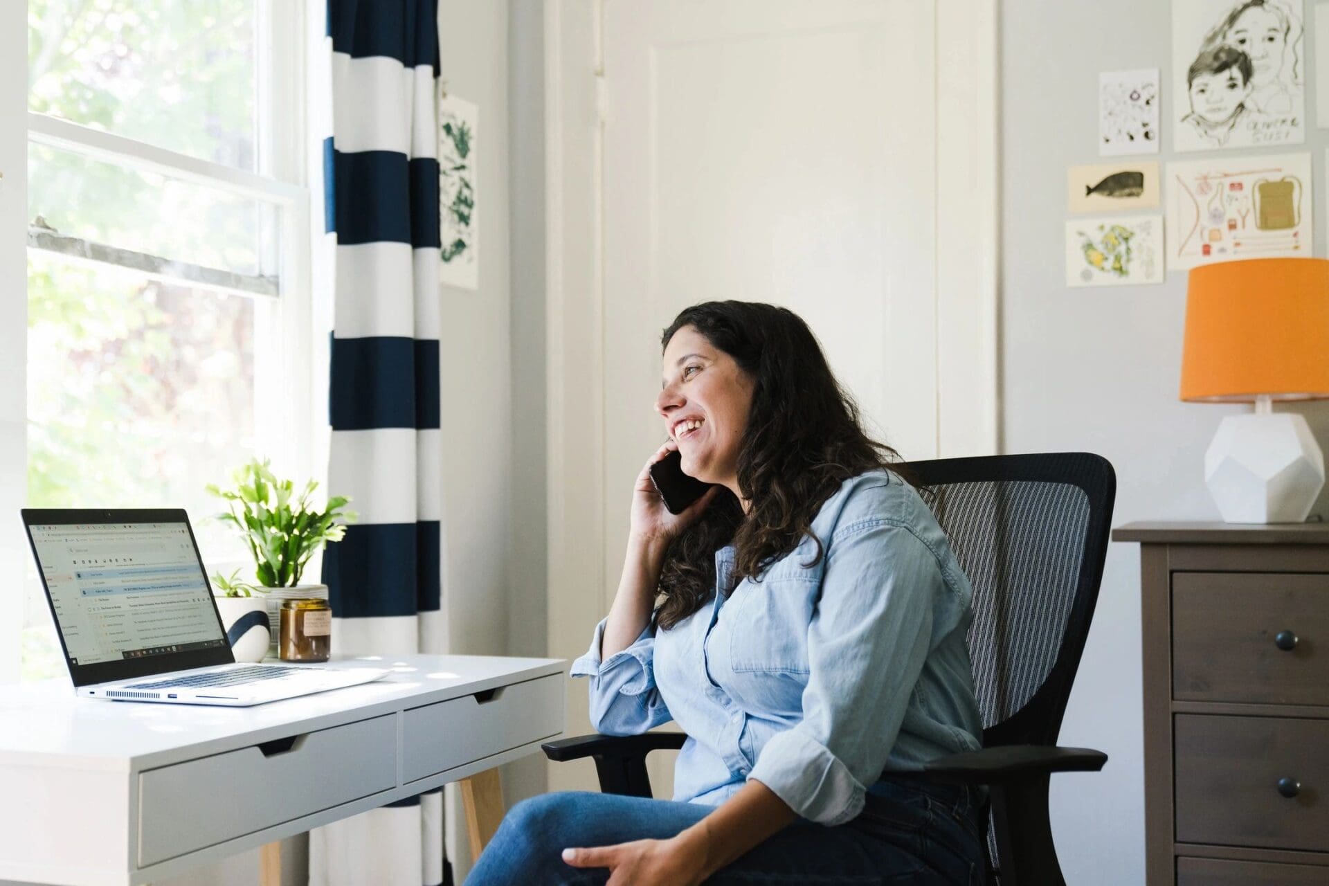 A woman talking on the phone while sitting in a chair in her home office.