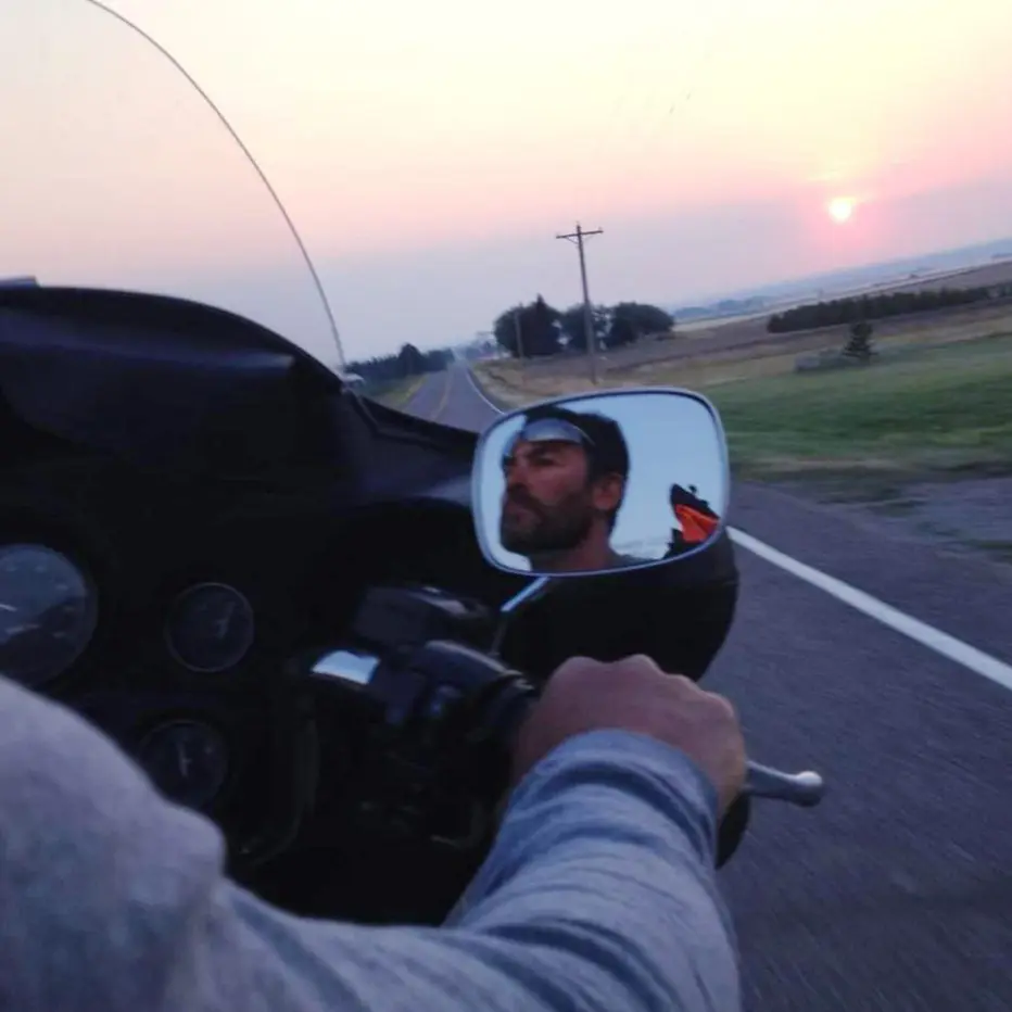 A man riding a motorcycle at sunset.