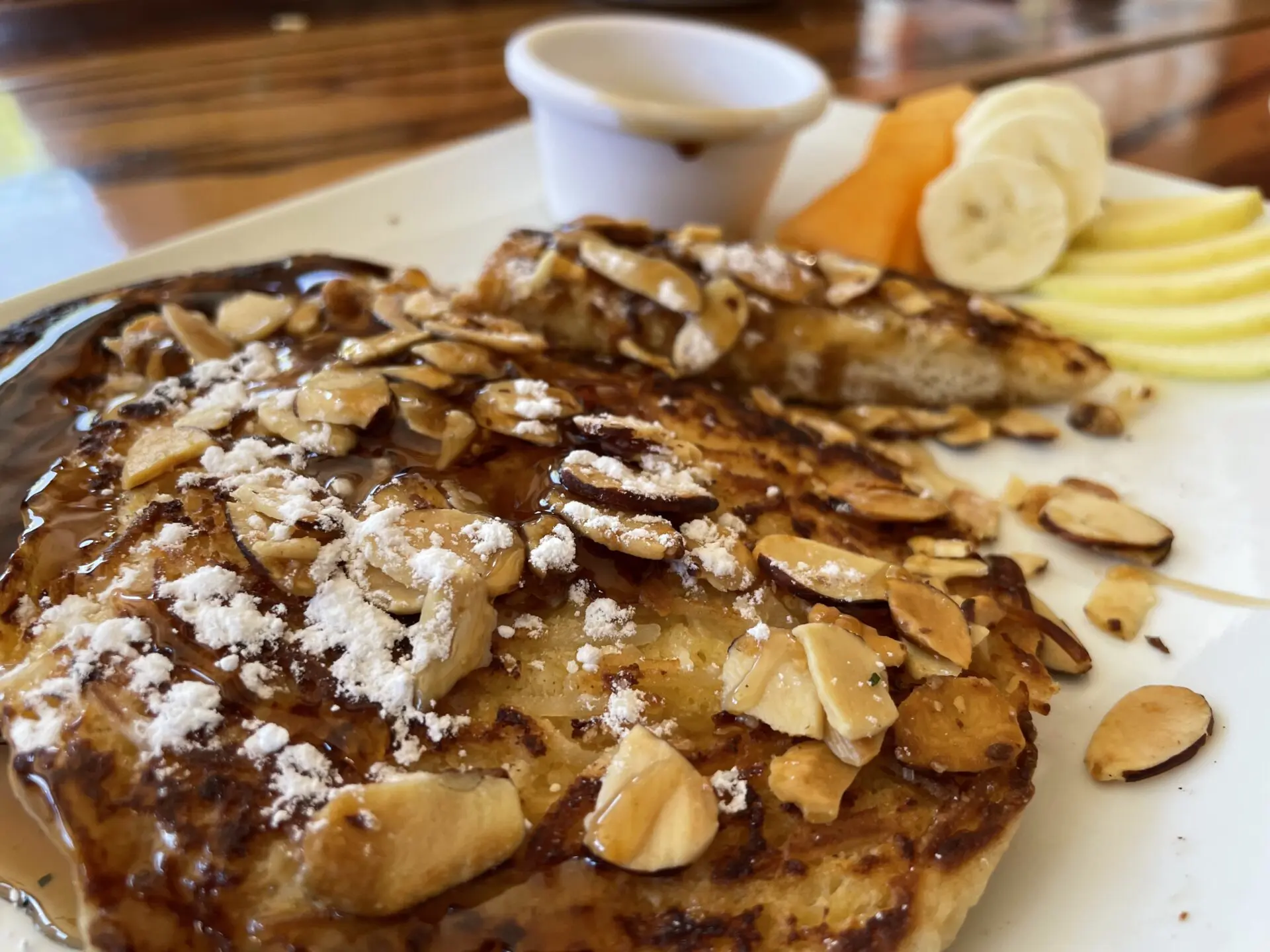 A plate of french toast with almonds and fruit.