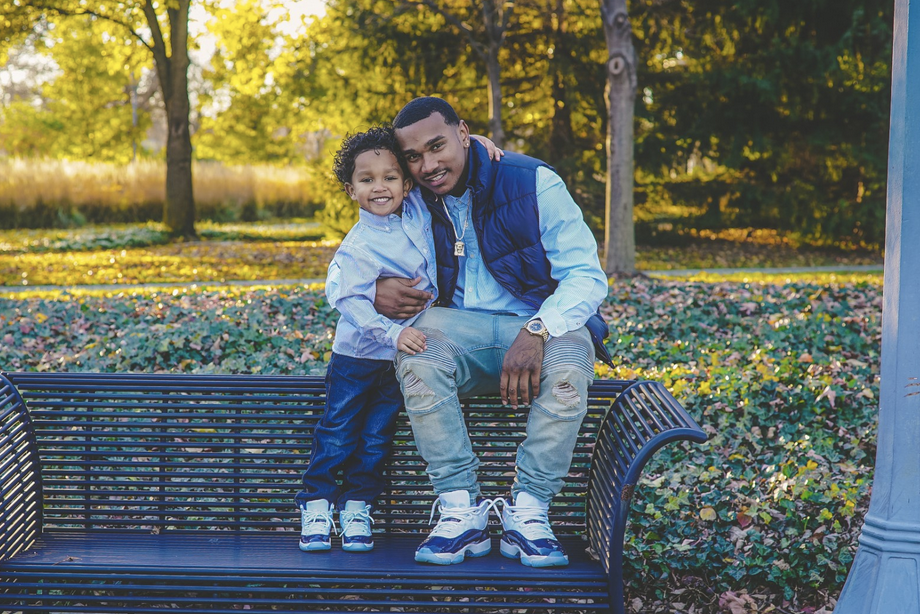 A man and his son sitting on a bench in a park.