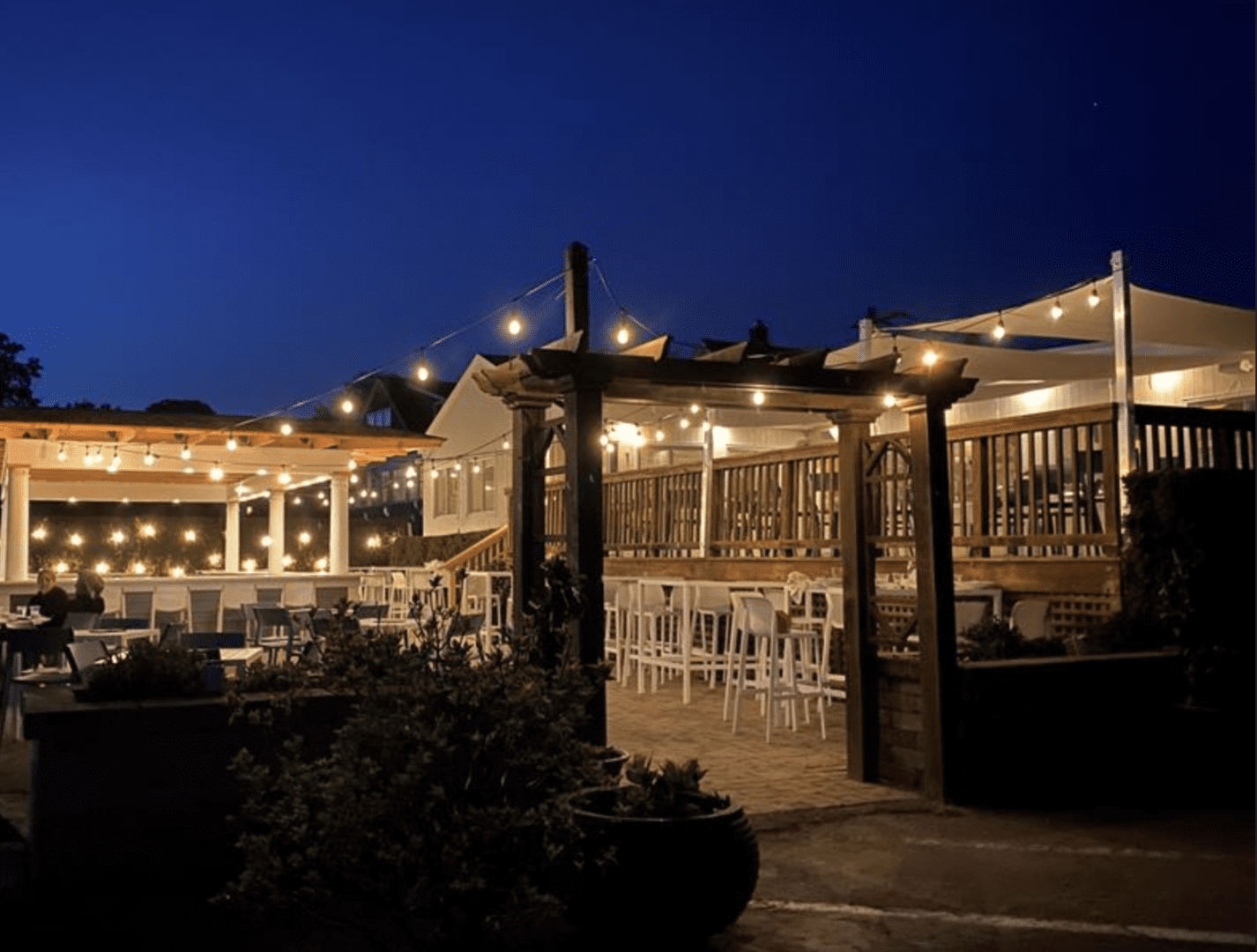 An outdoor dining area at night with string lights.