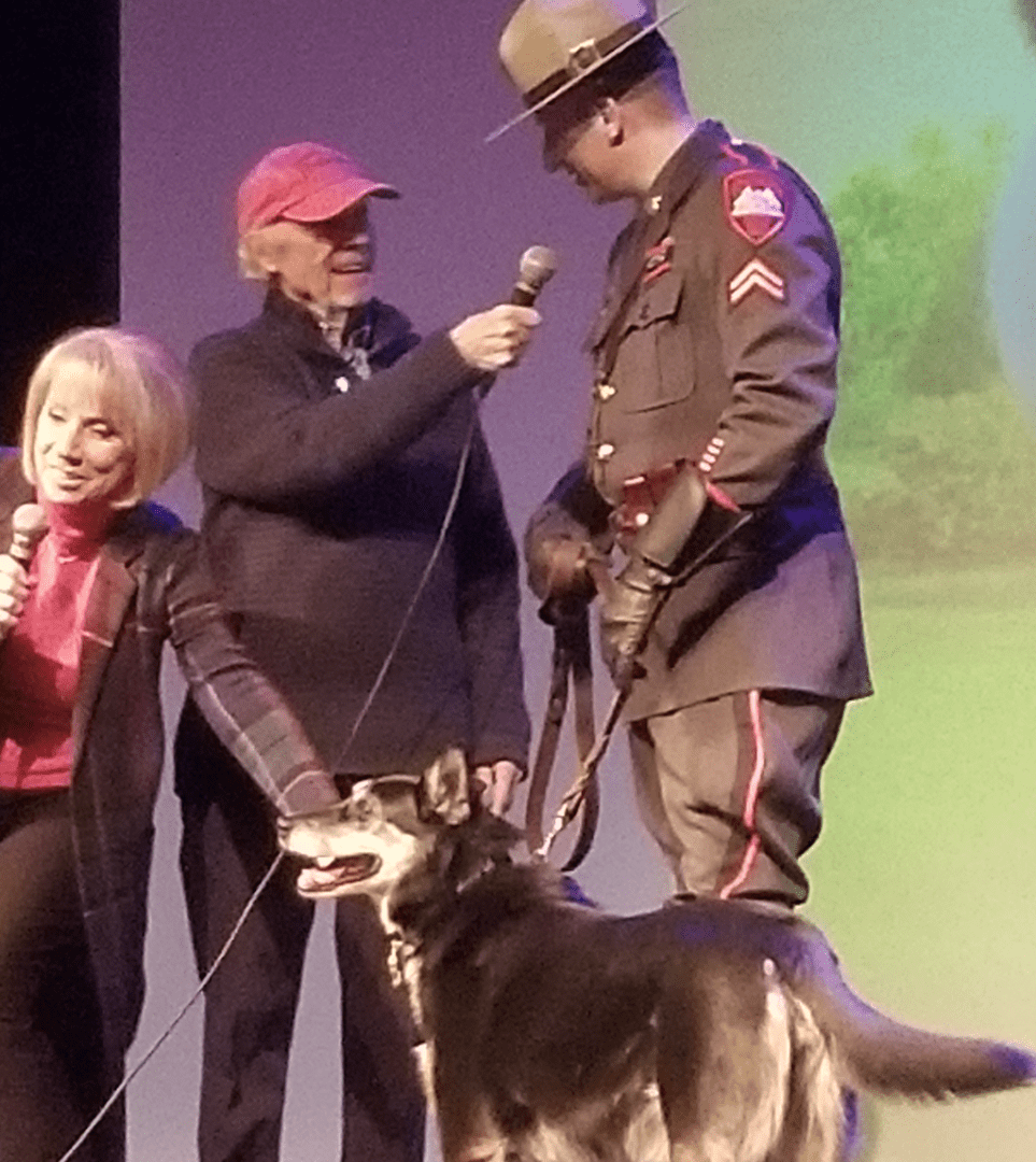 A man in a police uniform with a dog on stage.