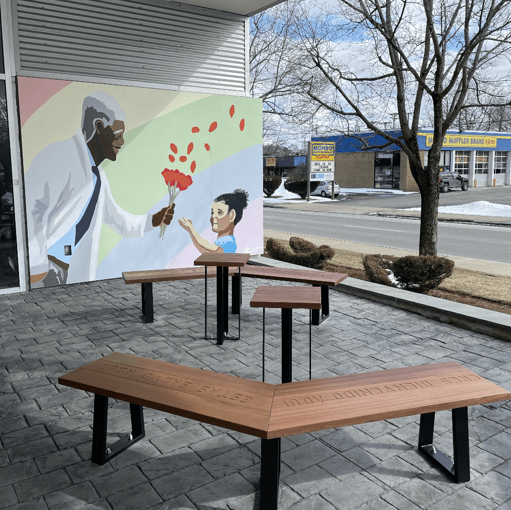 A bench in front of a building with a mural on it.