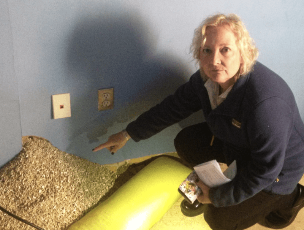 A woman kneeling down in a room with a bag of sand.