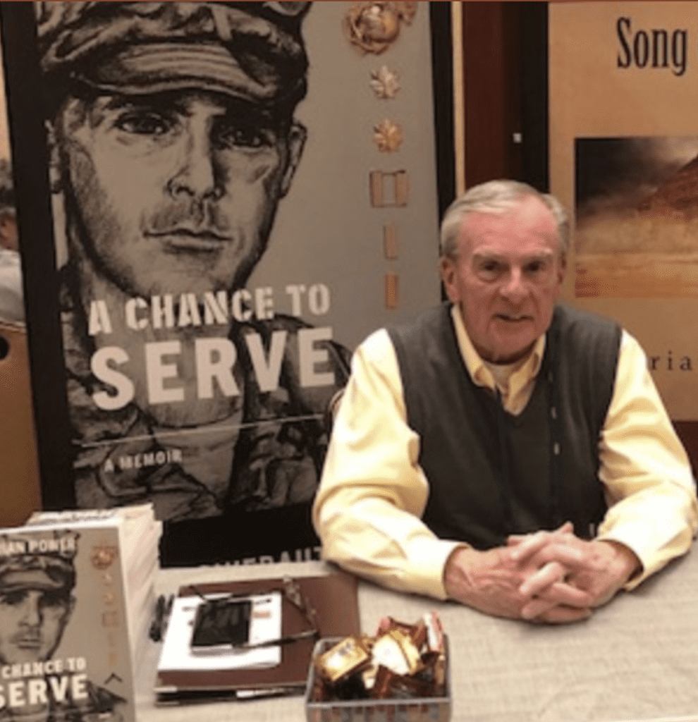 A man sitting at a table with a book in front of him.