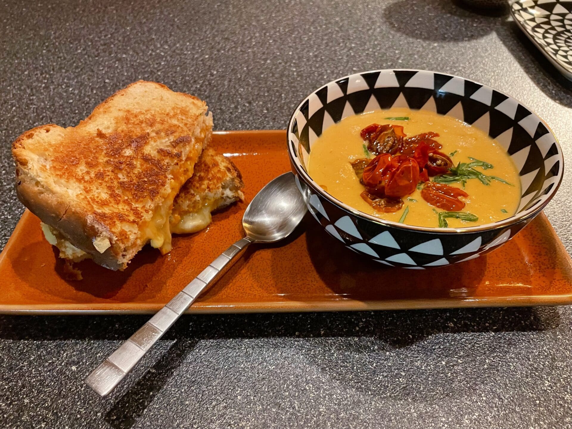 A plate with a grilled sandwich and soup on it, offering delicious recipes.