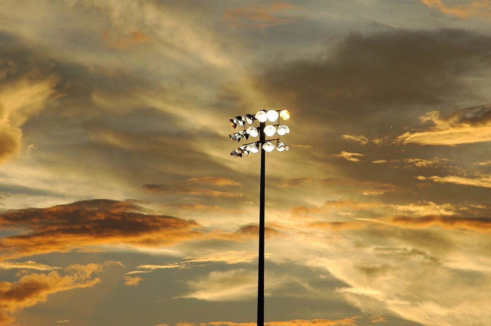 A stadium light with a cloudy sky in the background.