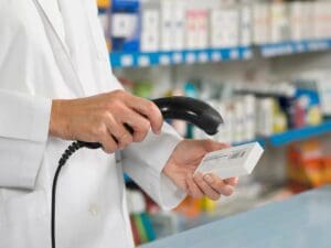 A pharmacist is using a mobile phone in a pharmacy.