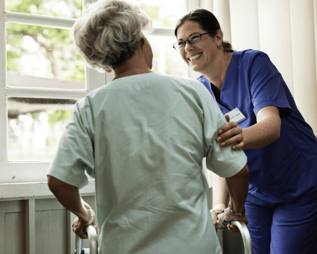 A nurse is helping an elderly woman with a walker.