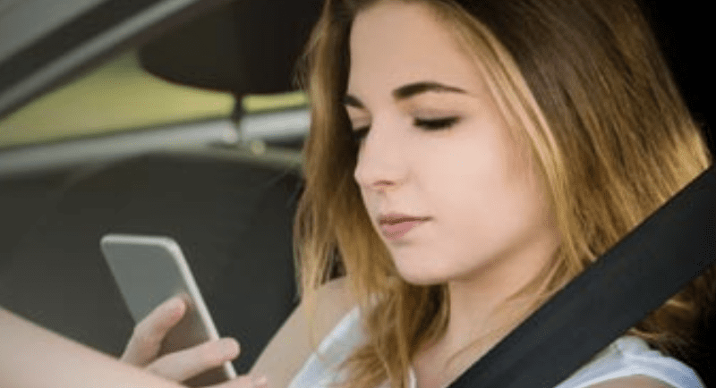 A woman using her cell phone in a car.