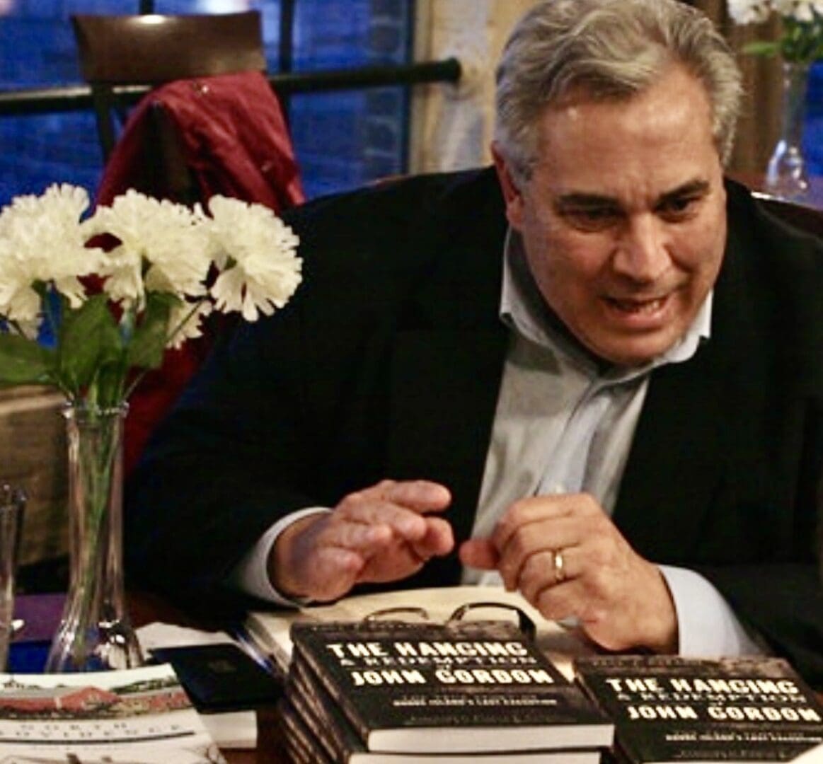 A man sitting at a table signing books.