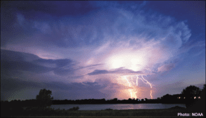 A lightning bolt is seen over a body of water.