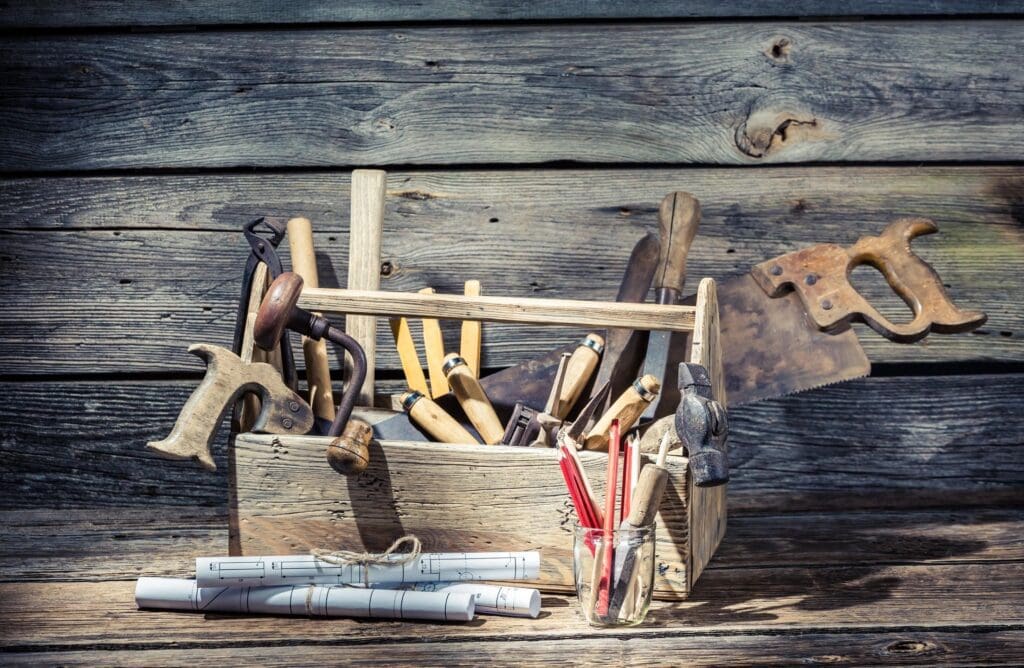 A wooden box full of tools on a wooden background.