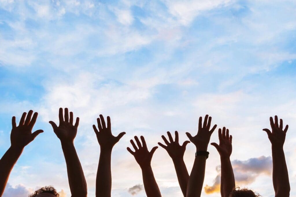 A group of people raising their hands up to the sky.